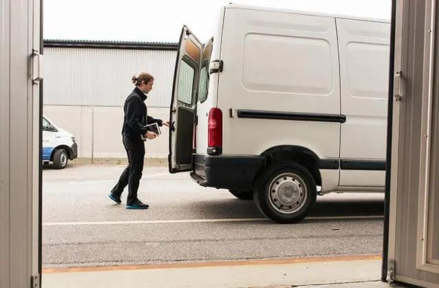 A person stood at the back of a white commercial vehicle.