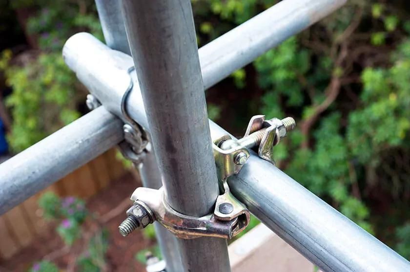 Close-up of a scaffolding metal pole and clamp for construction use.