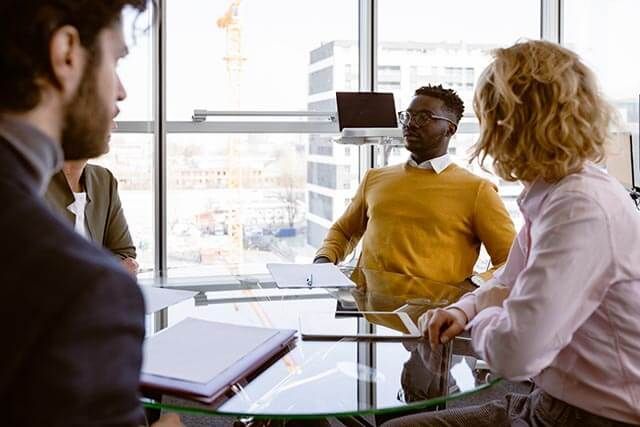 Four people seated at a table, reviewing documents in a professional office setting.