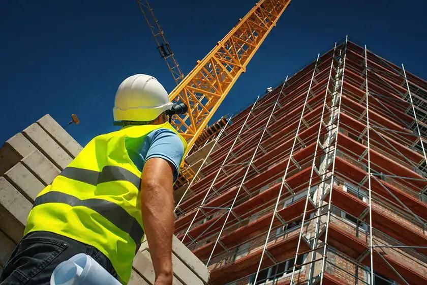 Construction worker inspecting scaffolding at a building under construction.