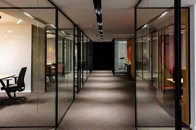 Modern office with a spacious hallway and glass walls creating multiple visible meeting areas.