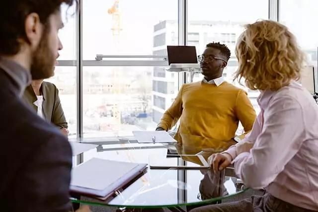 Four people seated at a table, reviewing documents in a professional office setting.