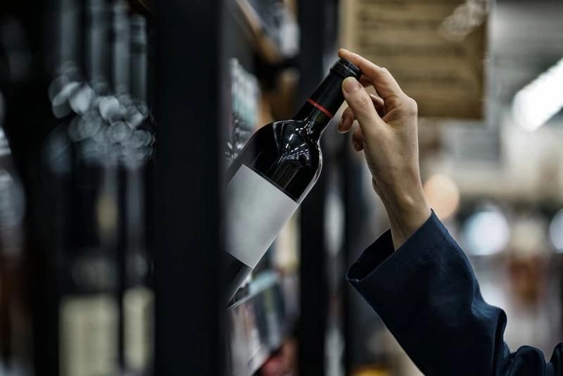 Bottle of wine being taken from a shelf