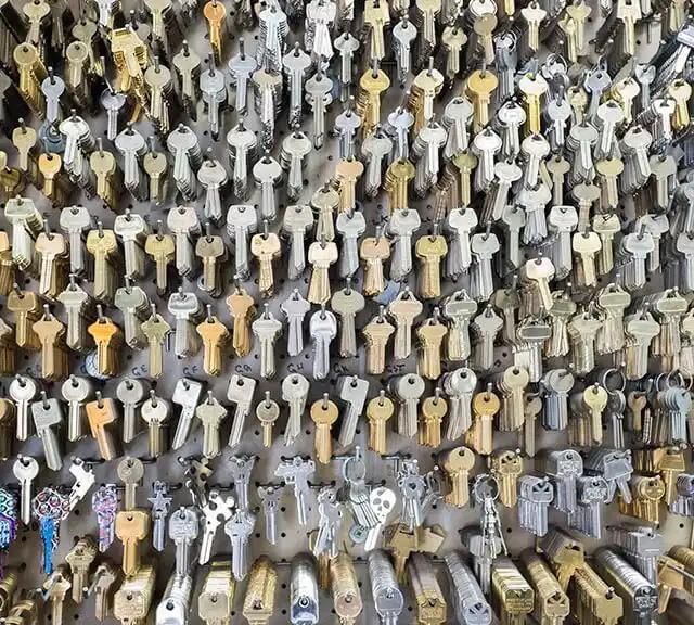 Wall display of various metal keys arranged neatly on hooks.