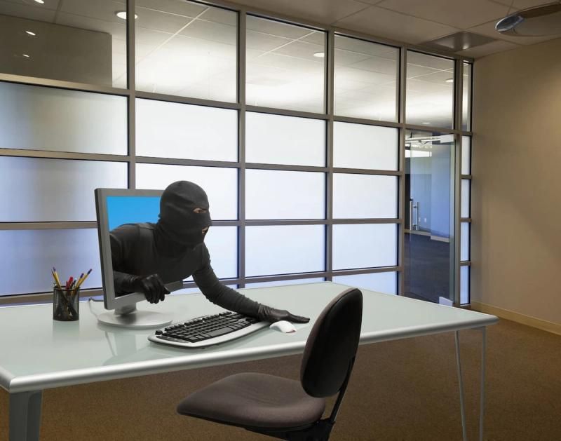 A suspicious figure emerging from a computer screen in an office