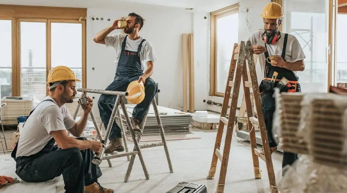 Three men wearing hard hats are working together on a construction site