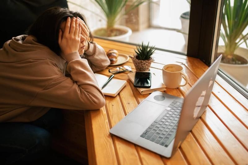 Person on a laptop with hands covering their face