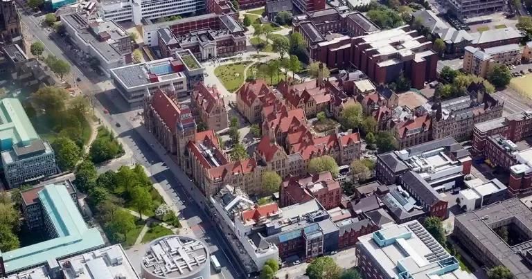 Aerial view of a university campus with red brick buildings and next to a big road.