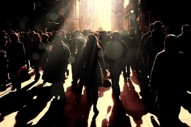 Lots of people casting shadows down a highstreet