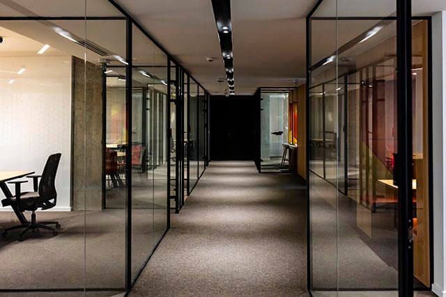 Modern office with a spacious hallway and glass walls creating multiple visible meeting areas.